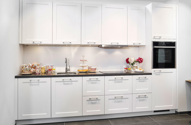 Rechte tijdloze keuken in witte kleurstelling, voorzien van veel opbergruimte door bovenkasten en lades.