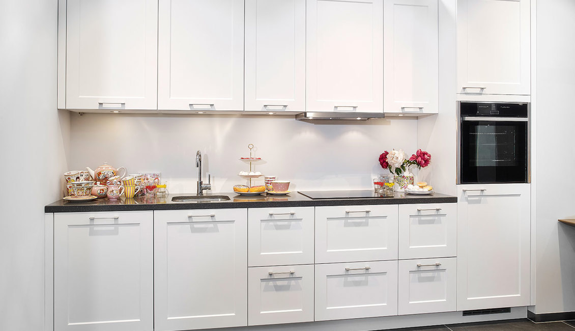 Rechte tijdloze keuken in witte kleurstelling, voorzien van veel opbergruimte door bovenkasten en lades.