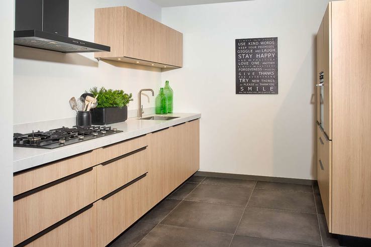 Parallelle houten keuken met greeploze fronten en betonlook keukenblad