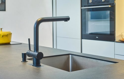 Zwarte kraan in de keuken, met betonlook keramiek aanrechtblad