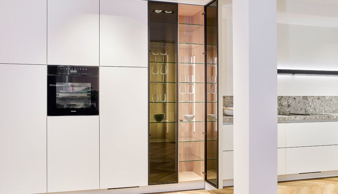 Witte luxe keuken met eiland, hoge kast met glasdeur