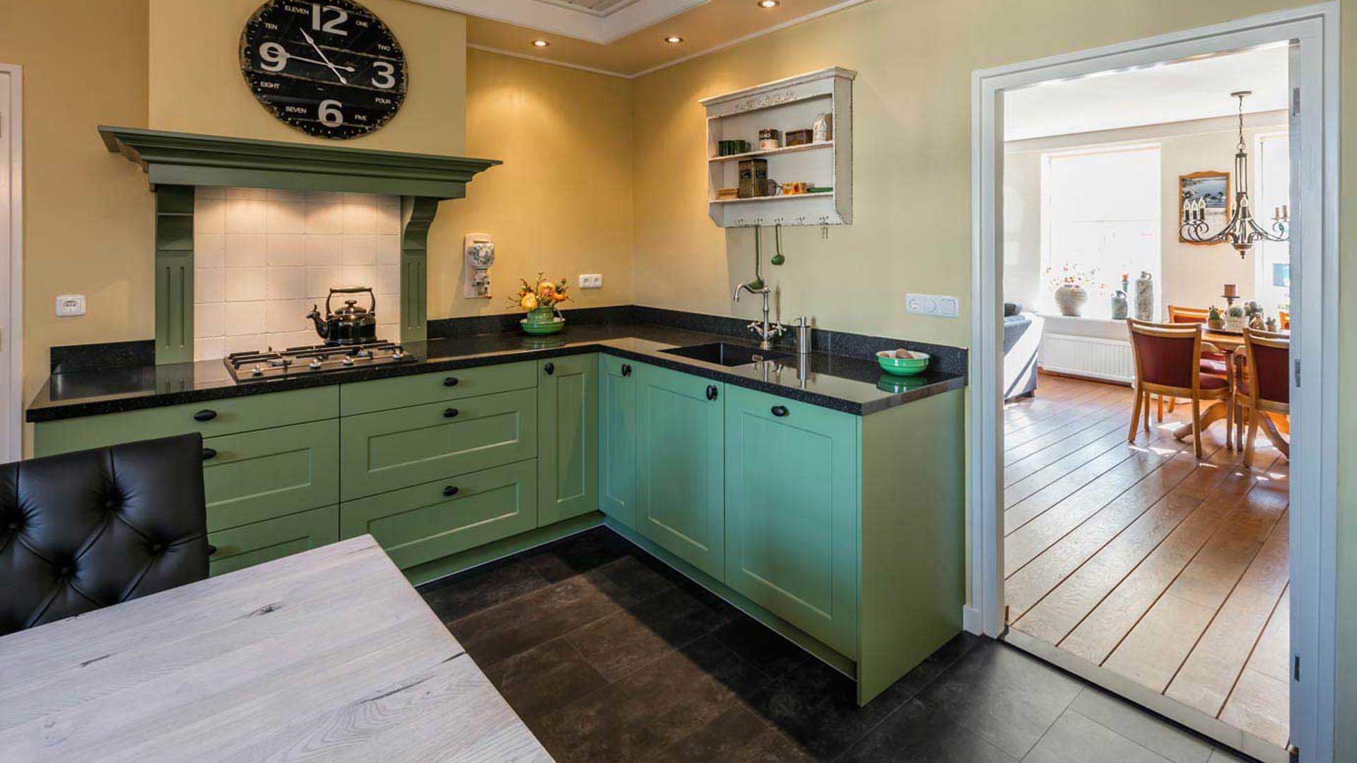 Landelijke keuken in groene kleur, met losstaande kastenwand.