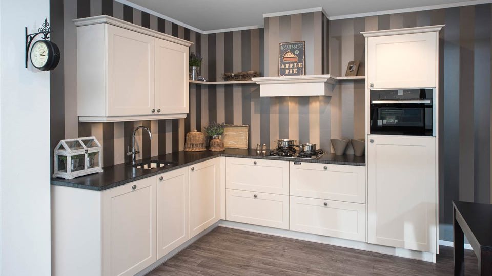 Witte klassieke hoekkeuken met schouw en bovenkasten