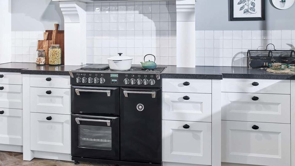Klassieke hoekkeuken met zwart fornuis, tegeltjes achterwand en schouw