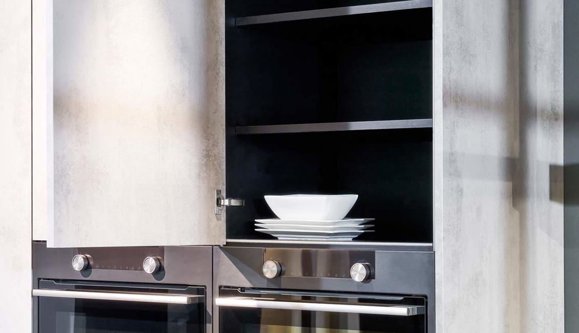Zwarte industriële keuken met betonkleurige kastenwand, donkere binnenkant
