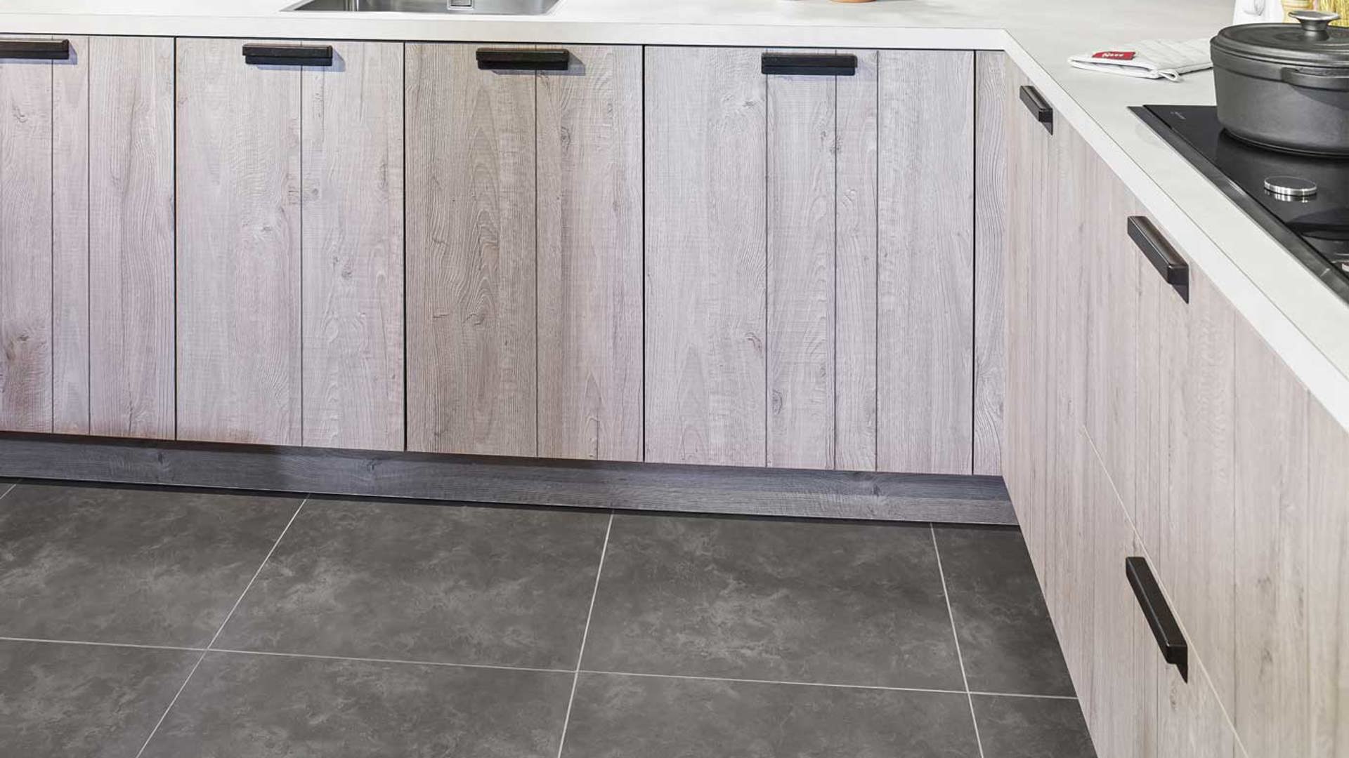 Industriële hoekkeuken met houten fronten en betonlook tegelvloer