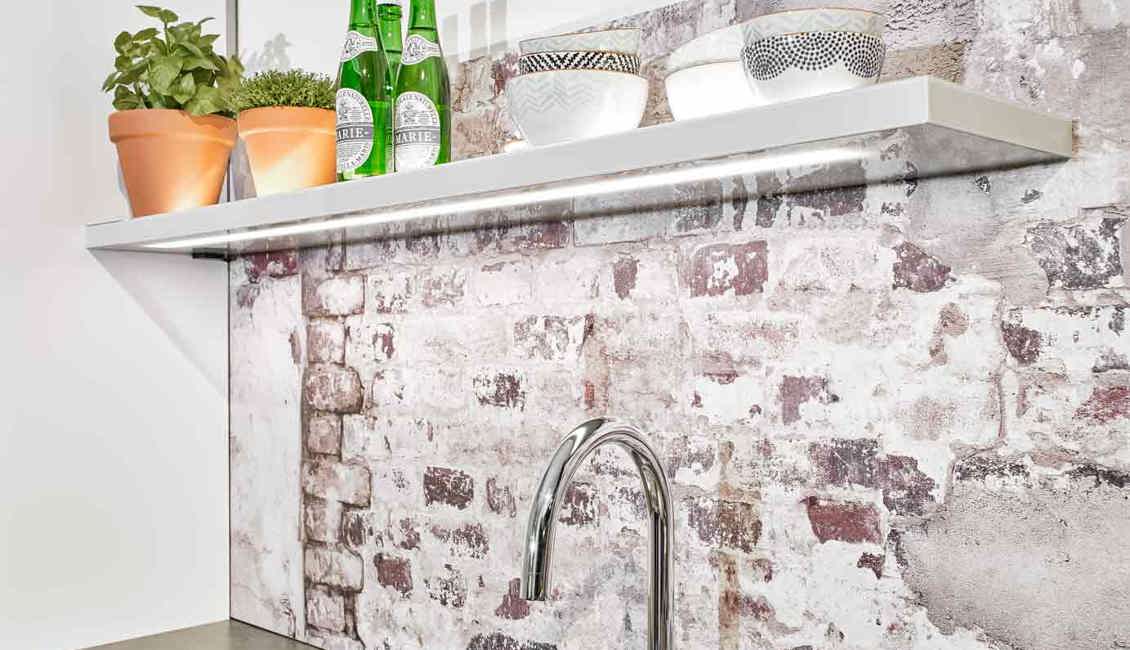 Deze witte keuken heeft diverse Scandinavische elementen, zoals dit steenbehang