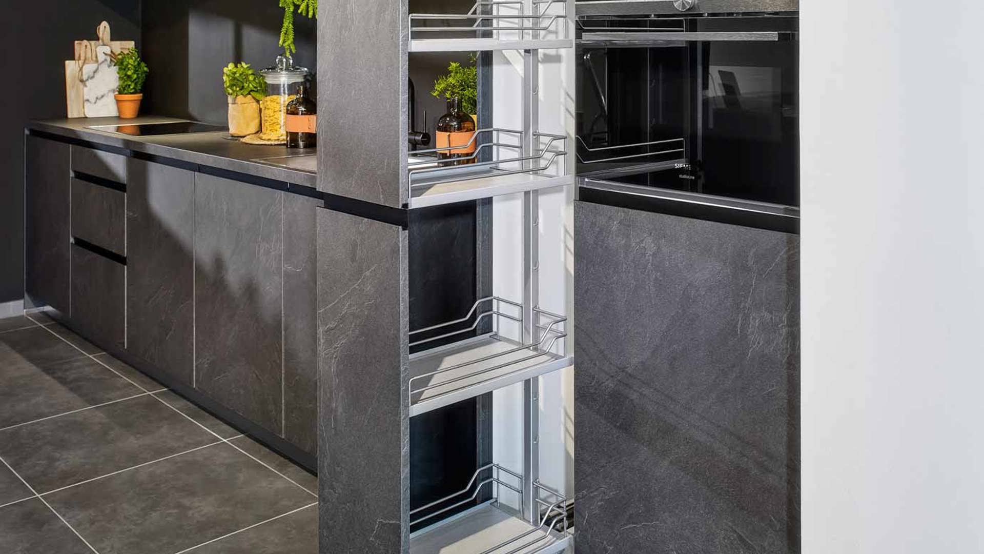 Deze keuken in leisteen grijs heeft een losstaande kast met apothekerskast
