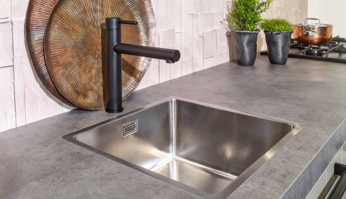 De parallelle keuken heeft een enkele spoelbak en is voorzien van een zwarte keukenkraan