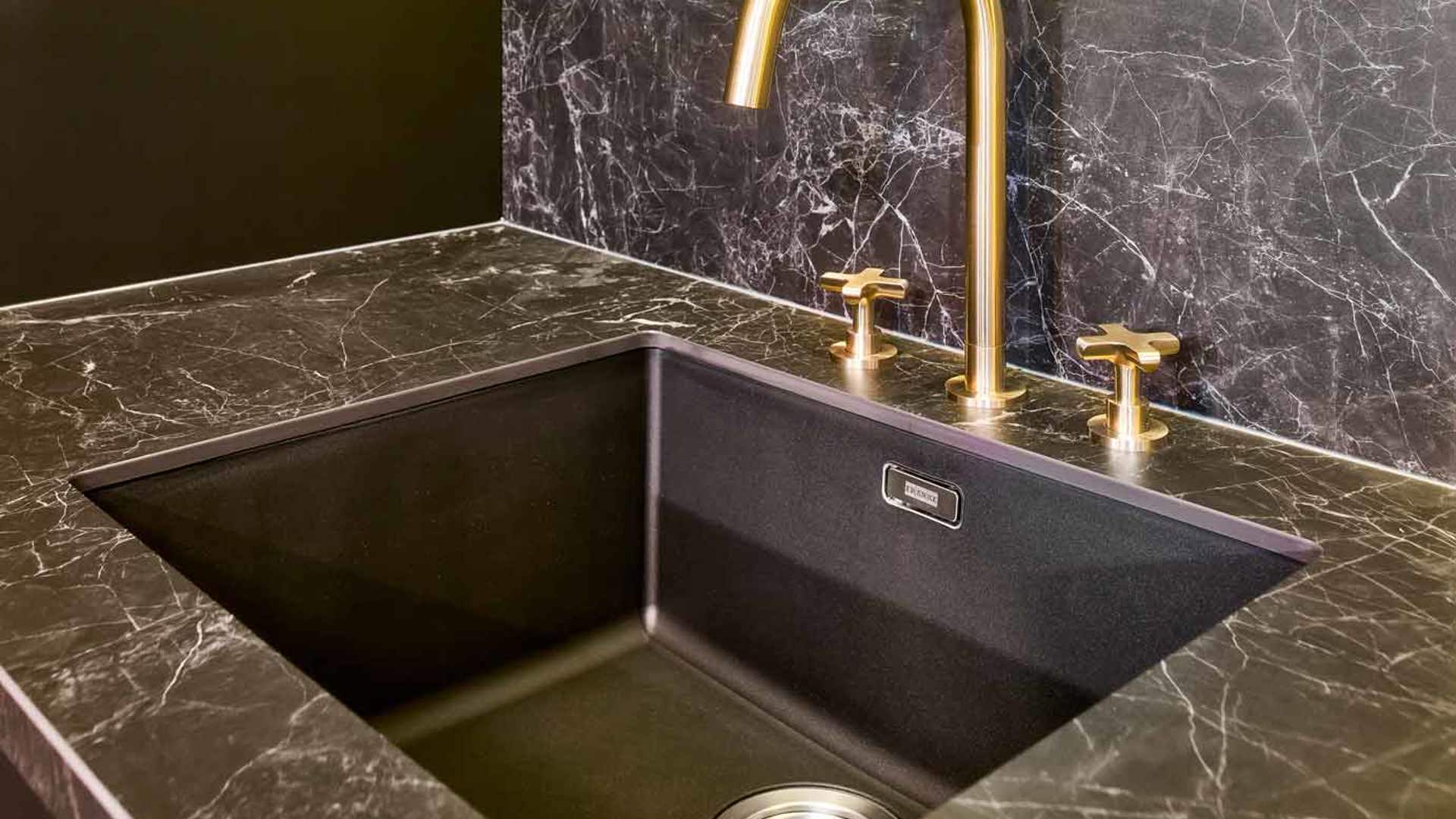 Deze moderne keuken is voorzien van marmeren, zwarte en gouden kleuren