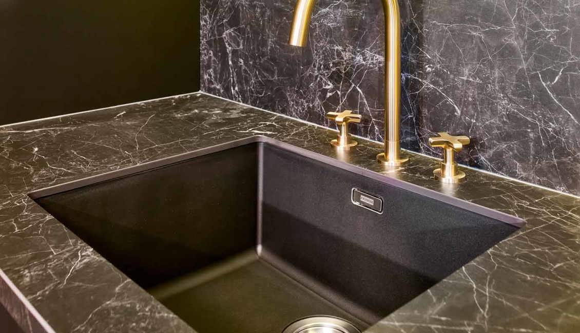 Deze moderne keuken is voorzien van marmeren, zwarte en gouden kleuren
