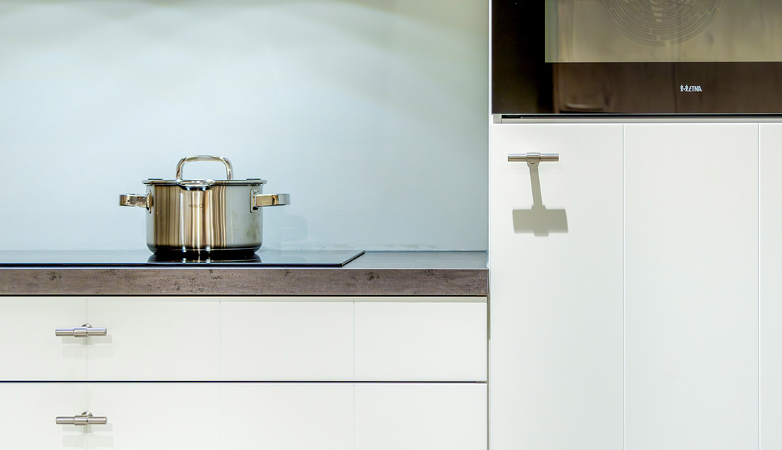 Inductiekookplaat in moderne witten keuken met grepen