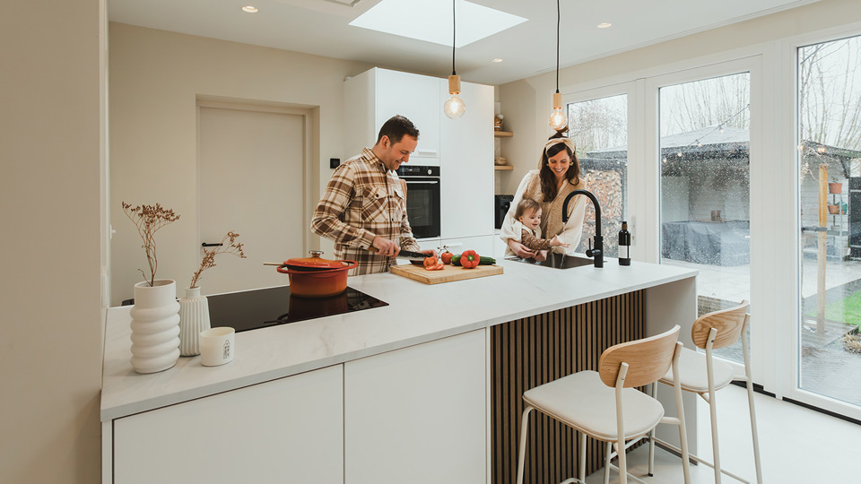 Familie Pieper en dochter in witte moderne keuken met schiereiland en inductiekookplaat