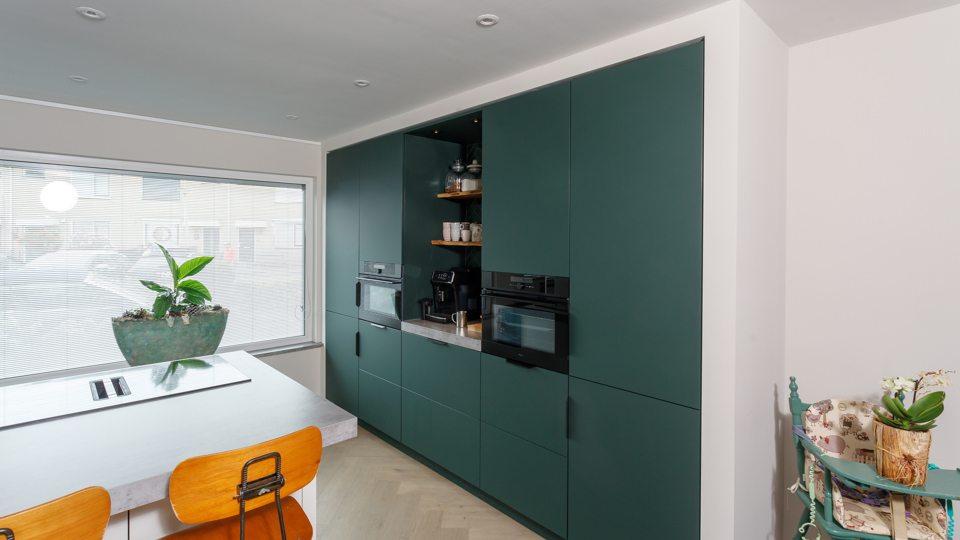 Groene hoekkeuken met kastenwand